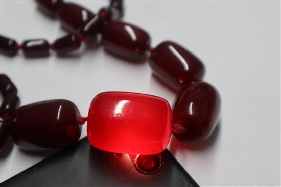 A single strand graduated simulated dark cherry amber necklace, gross weight, 98 grams,